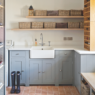 Utility room and sink. Pair of wellys by blue cabinets and basket storage