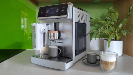 Philips Cafe Aromis Series 8000 coffee maker on kitchen counter with coffee and house plant