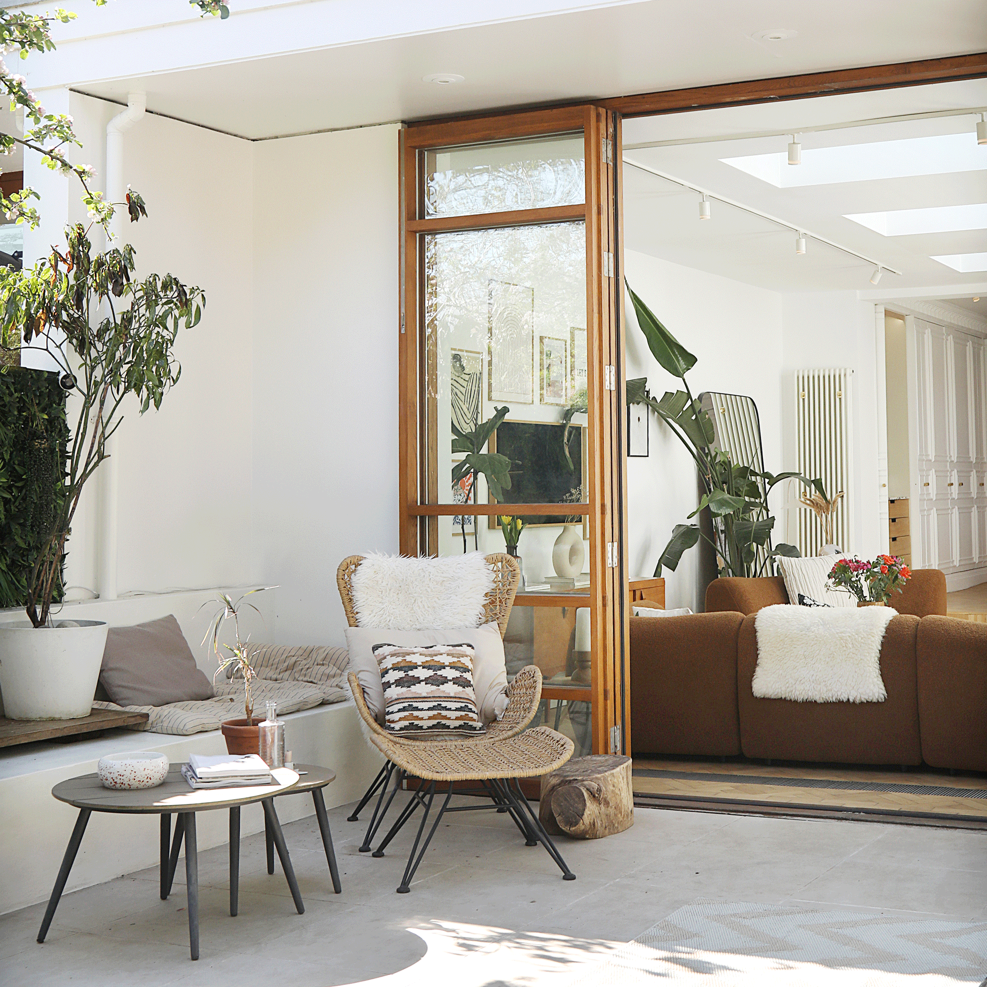 a garden with patio area with a lunger chair and bifold doors into a house