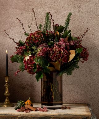 A smoky vase filled with a large deep red bouquet