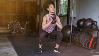 Woman performs goblet squat with a kettlebell