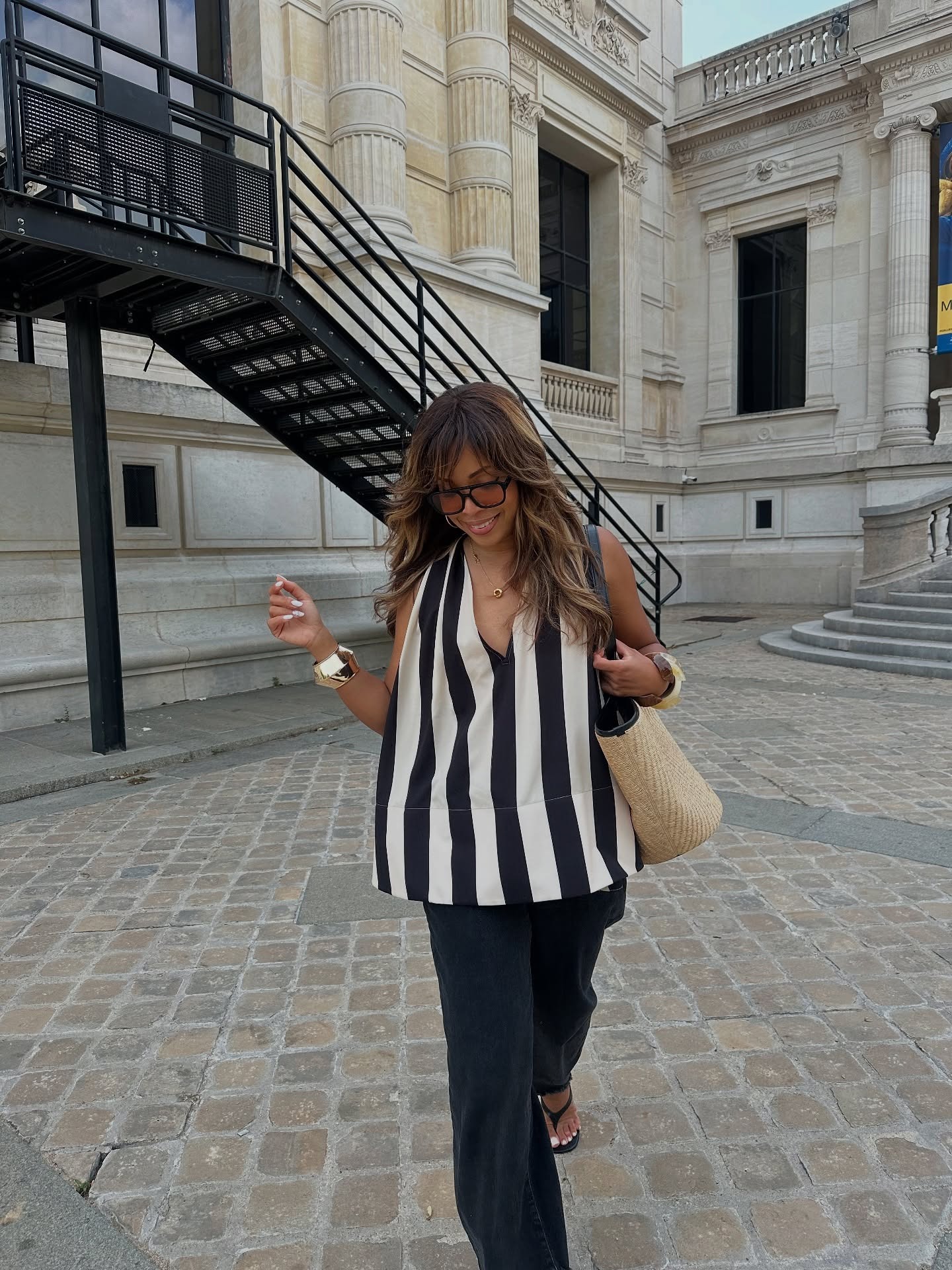 A woman wearing a stripe top with black trousers and sandals with a soft white pedicure