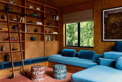 A media room with a large, bright blue custom seating area and a bookshelf