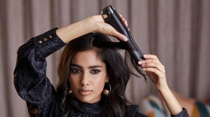 A woman styling her hair with one of the best hair straighteners – the GHD Unplugged styler