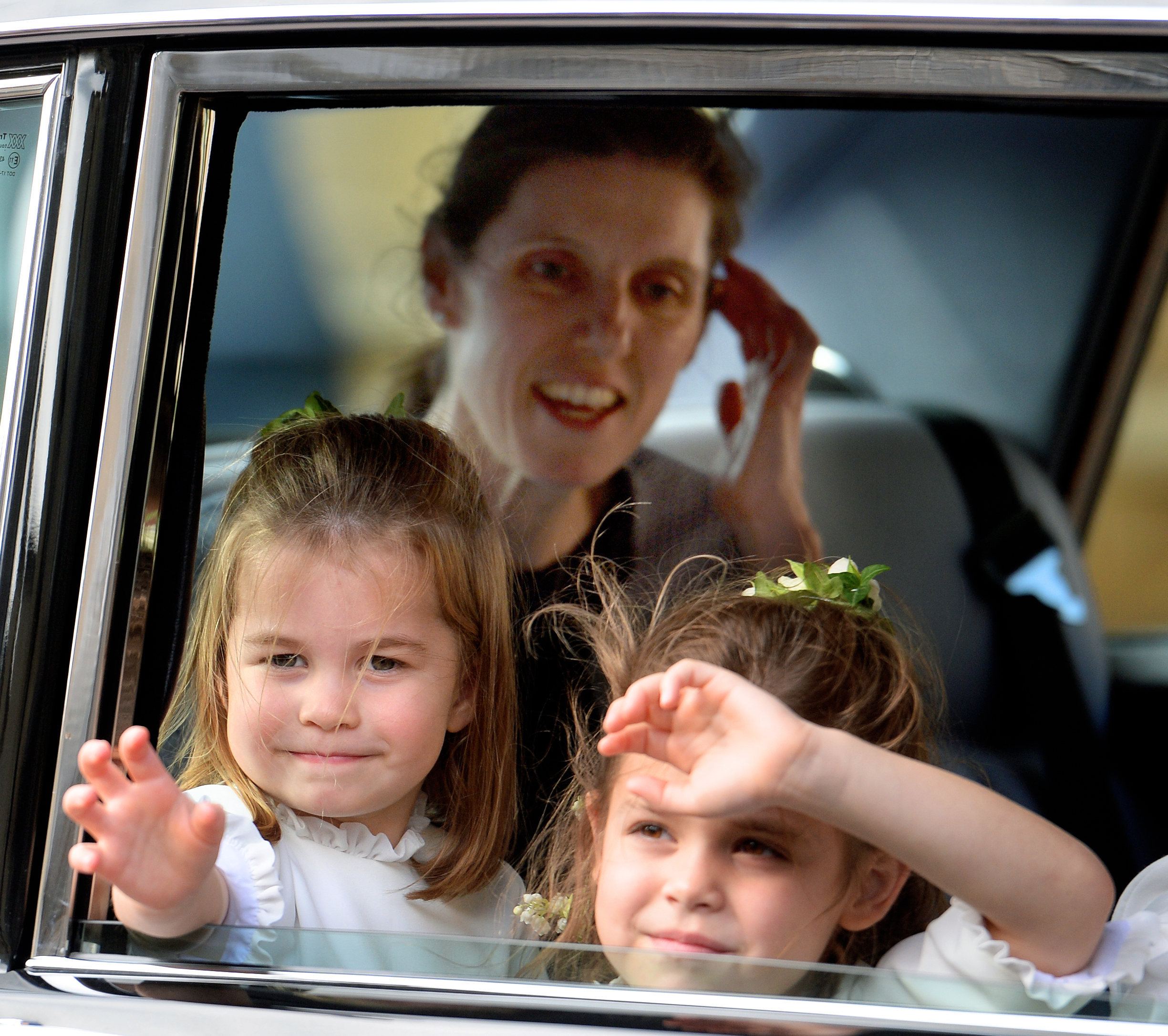 Nanny Maria in a car with Princess Charlotte and Theodora Williams, both waving out an open window