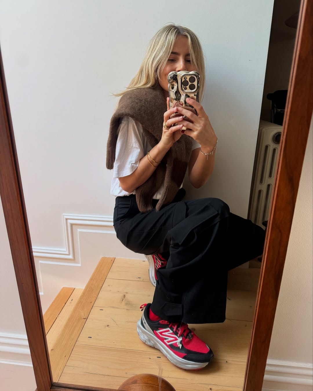 Influencer Lucy Williams in black wide-leg pants and red sneakers.