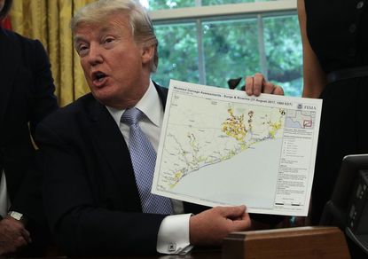 President Donald Trump holds up a diagram showing damage assessments in the Oval Office of the White House September 1, 2017 i