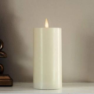 One white flameless candle sitting on a white mantle.