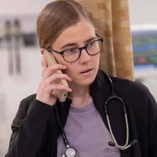 Taylor Dearden as Mel King talks on a cellphone while standing in an emergency room, in 'The Pitt.'