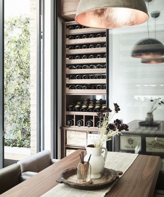 A modern kitchen with wooden dining table and exposed wine fridge