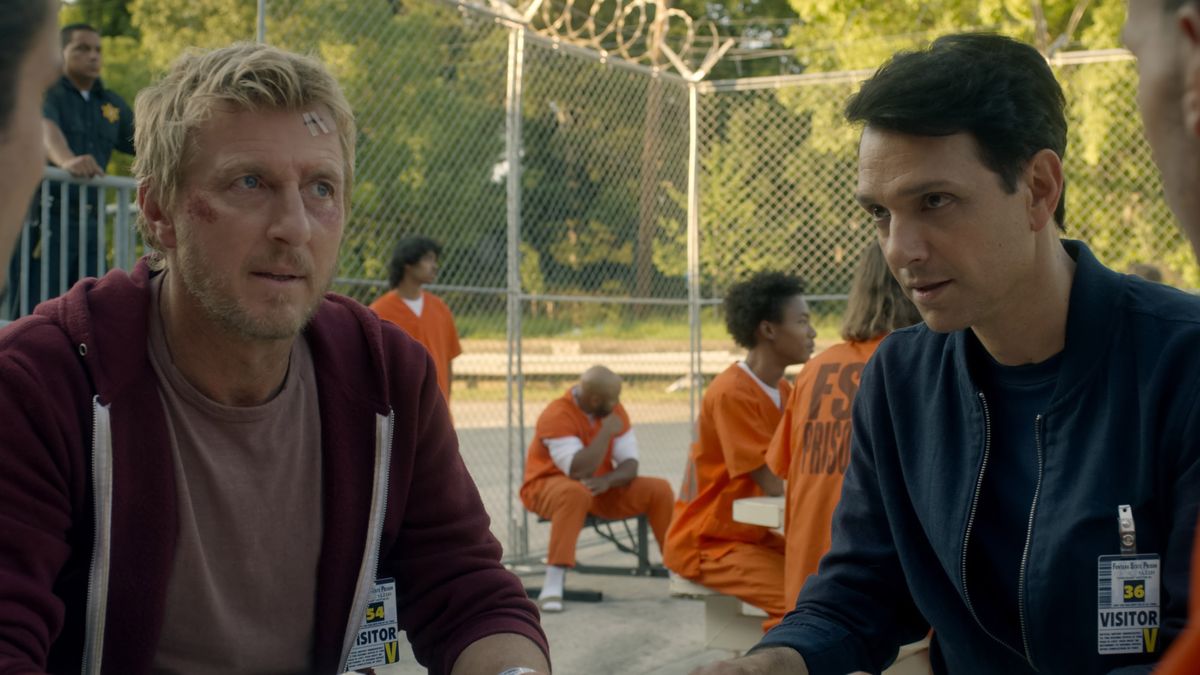 Johnny Lawrence and Daniel LaRusso at a table in a prison in Cobra Kai, which returns to Netflix in 2021.