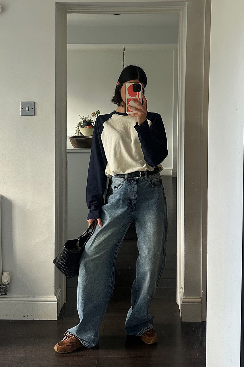 a woman wearing black and white longsleeve, jeans, and brown sneakers