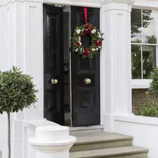 house entrance with black door and wreath