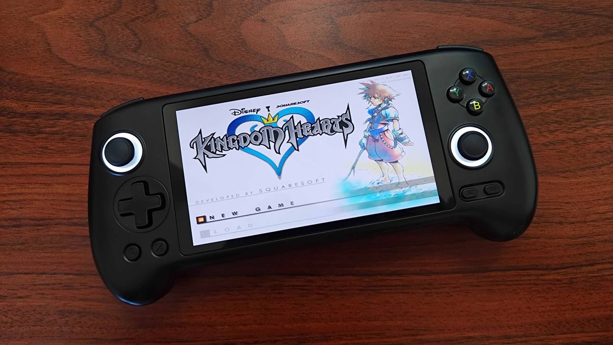 Anbernic RG556 handheld on woodgrain desk with Kingdom Hearts menu screen displayed.