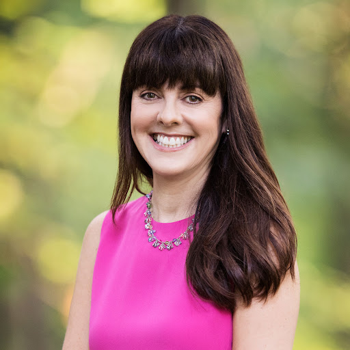 a white woman with long, brown hair posing for a headshot and wearing a hot pink blouse