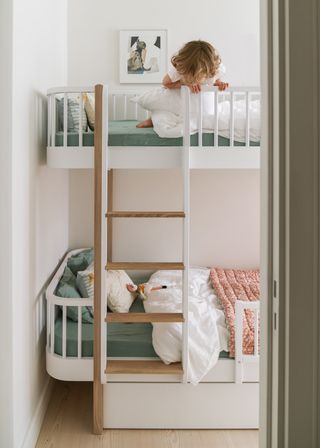 kids room bunks with a little girl on the top, green sheets