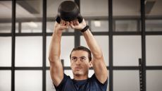 Man wearing t-shirt doing a kettlebell swing in a gym
