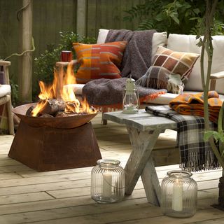 outdoor terrace with open fire pit and rustic seating with cosy blankets