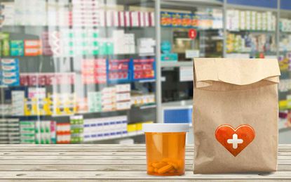A bottle of pills, a bag with prescriptions sit on the counter of a pharmacy