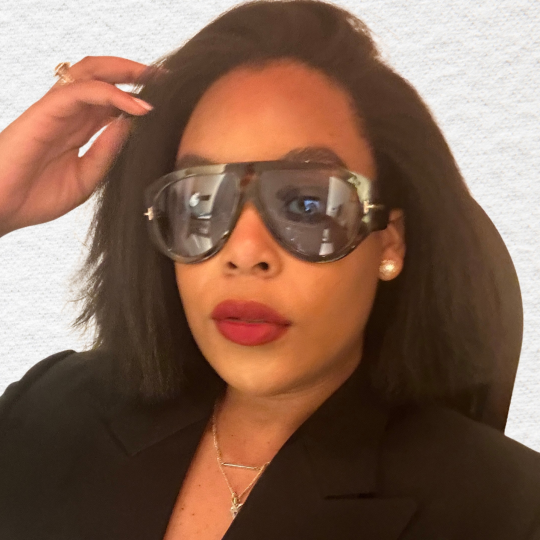 Ariel Baker's headshot. She is wearing red lipstick and sunglasses. 