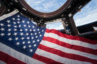The American flag floats in the cupola aboard the International Space Station.