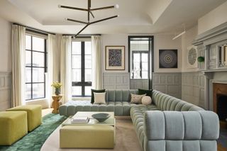 A living room with a large pillowy blue sofa, light blue painted millwork, and a light green coffee table