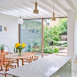 kitchen diner with scandi table and chairs large open patio doors and yellow flowers in a vase