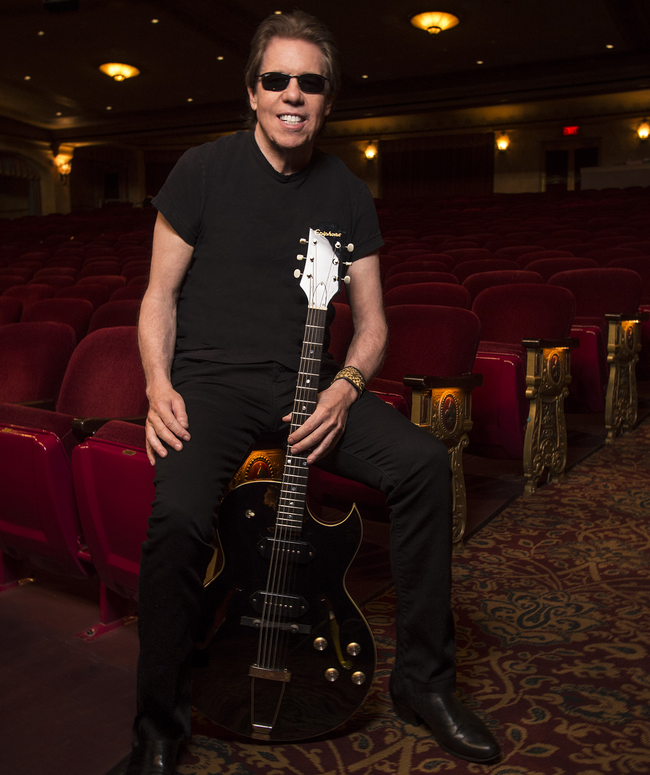 George Thorogood poses in a theater with one of his Epiphone ES-125 guitars