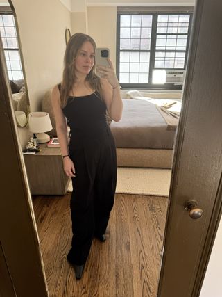 Nikki wears a black tank top and black trousers.