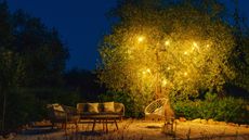 Solar lights in a tree next to an outdoor sofa set and swing seat 