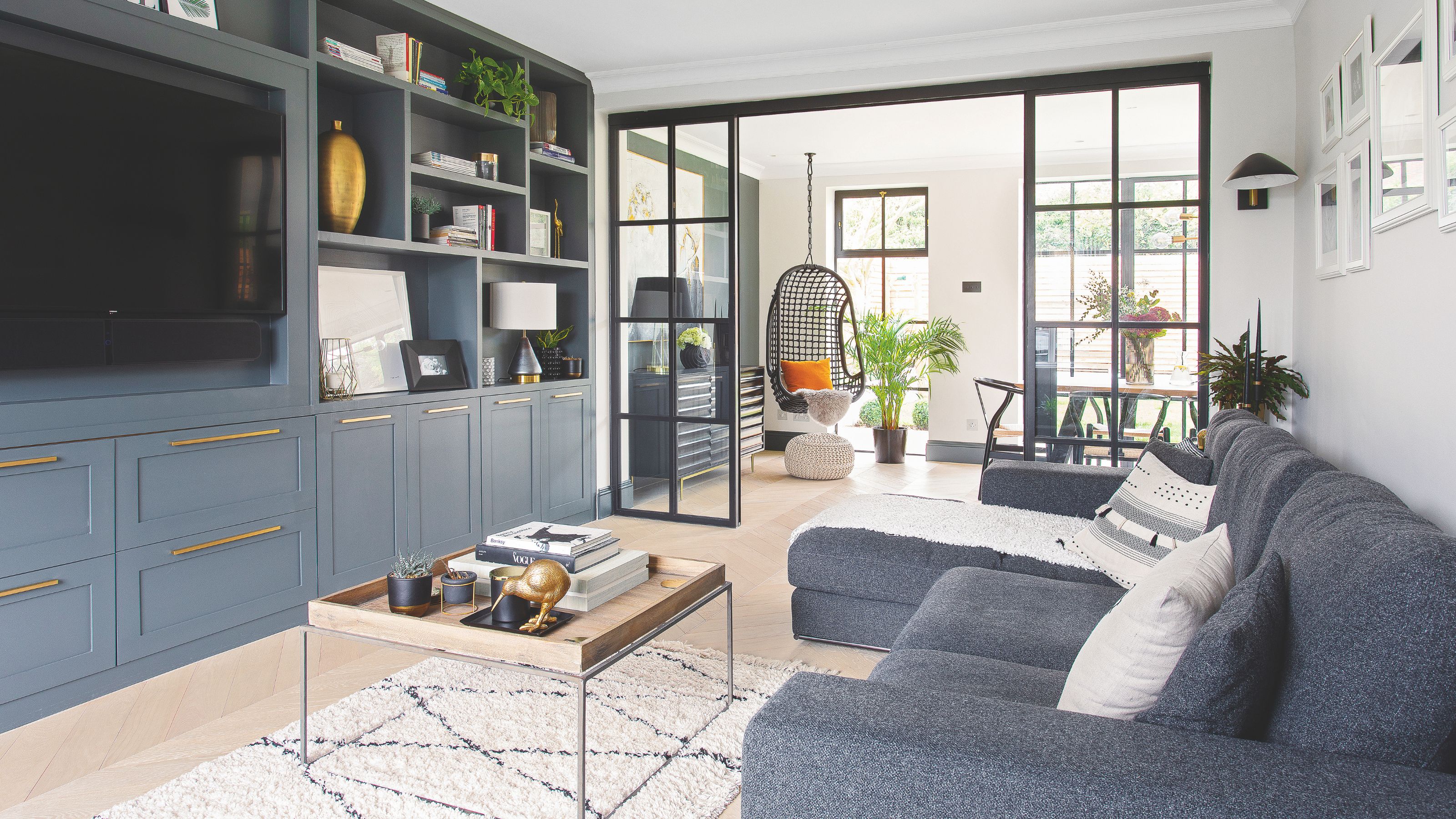 Open plan living and dining area with a blue sofa and blue fitted media wall