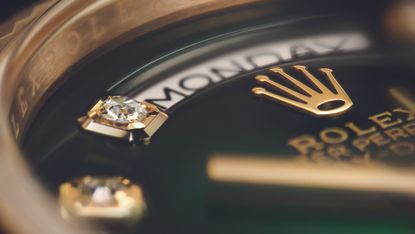 Close up image of a gold Rolex Day Date with diamond indices and green dial