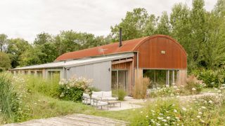 A barn conversion with a steel, Corten roof surrounded by wildflower meadows