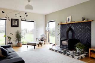 Living room with black herringbone tiled fireplace by Bert & May