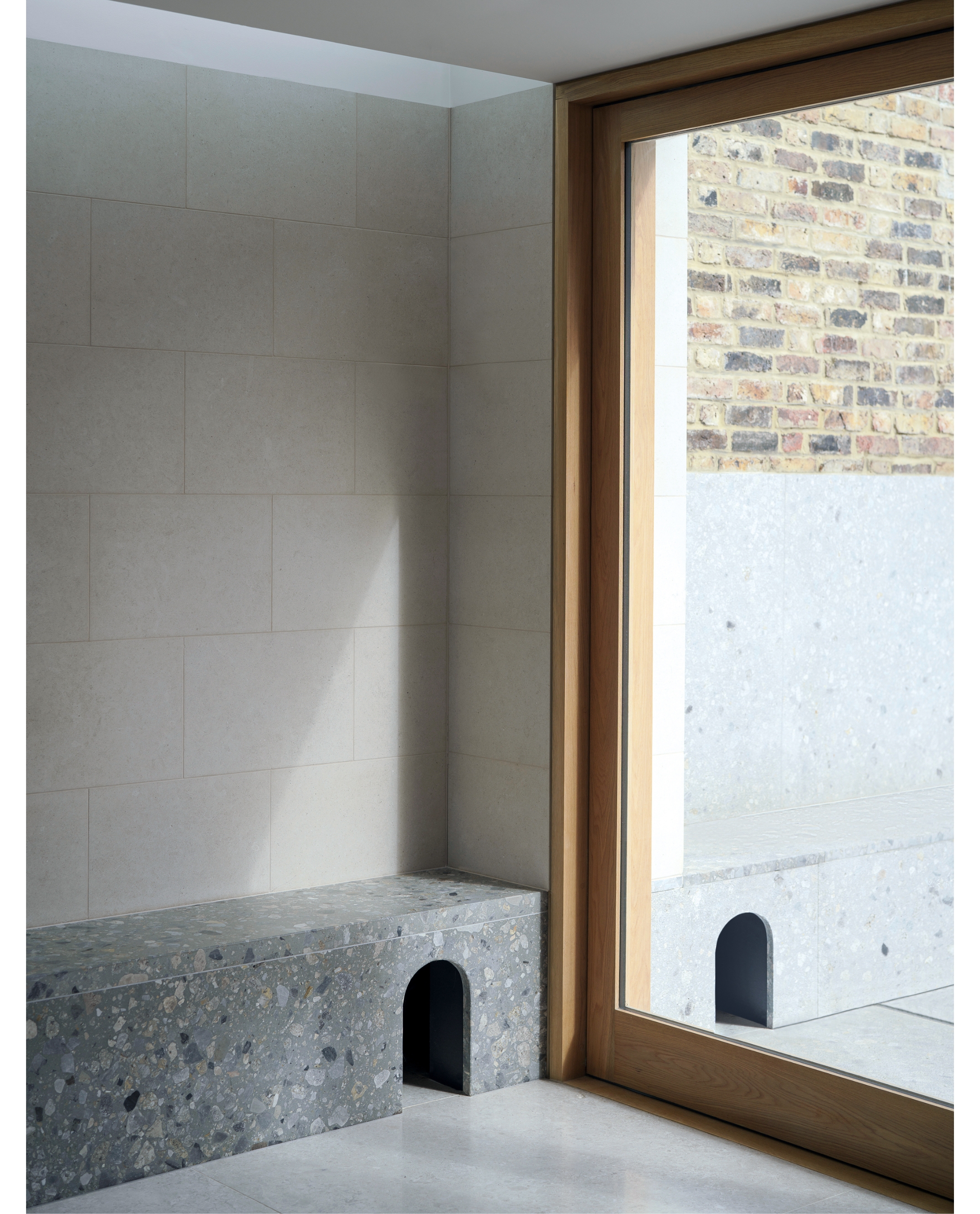 A grey stone tunnel along the floor, against the wall, leading to the outside space as seen through the glass back doors. Two cartoon style arches are either side to create a stylish cat door.