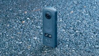 Ricoh Theta A1 360 camera on a tarmac surface, covered in water droplets