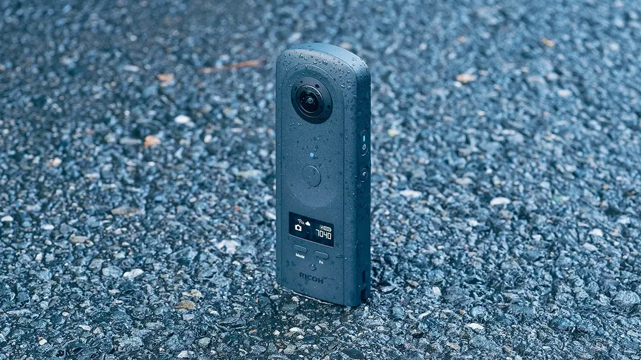Ricoh Theta A1 360 camera on a tarmac surface, covered in water droplets