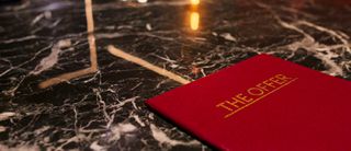 'The Offer' red book on a marble surface.