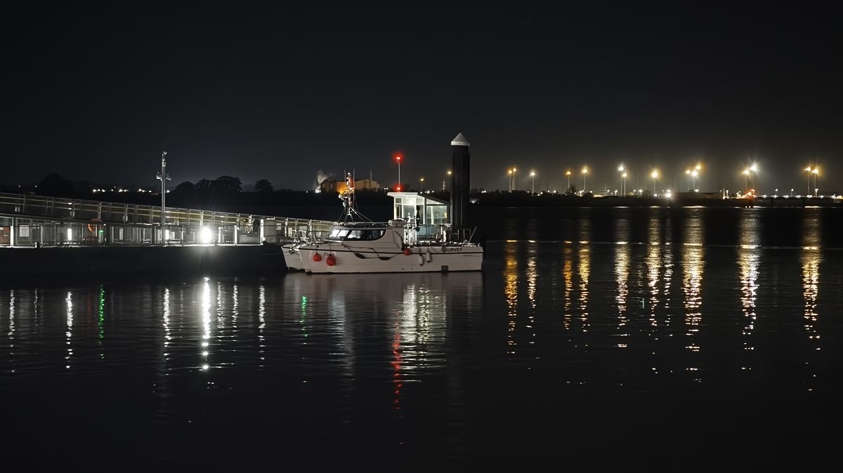 Night photo of boat moored on a jetty on a river at night