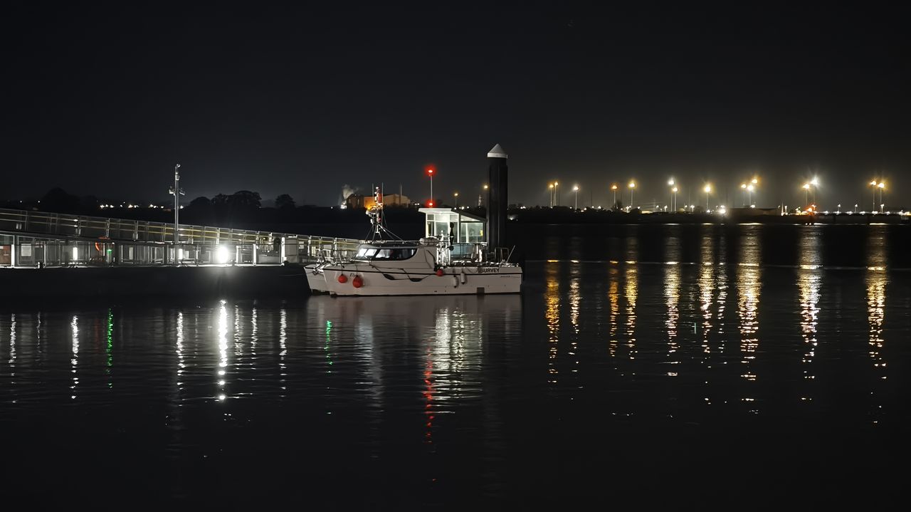 Night photo of boat moored on a jetty on a river at night