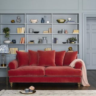 living room with velvet sofa and storage shelves