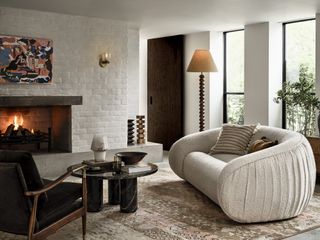 A living room with fireplace, sconce and floor lamp