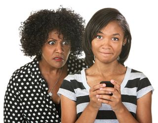 a mom looking over her daughter's shoulder at a cell phone