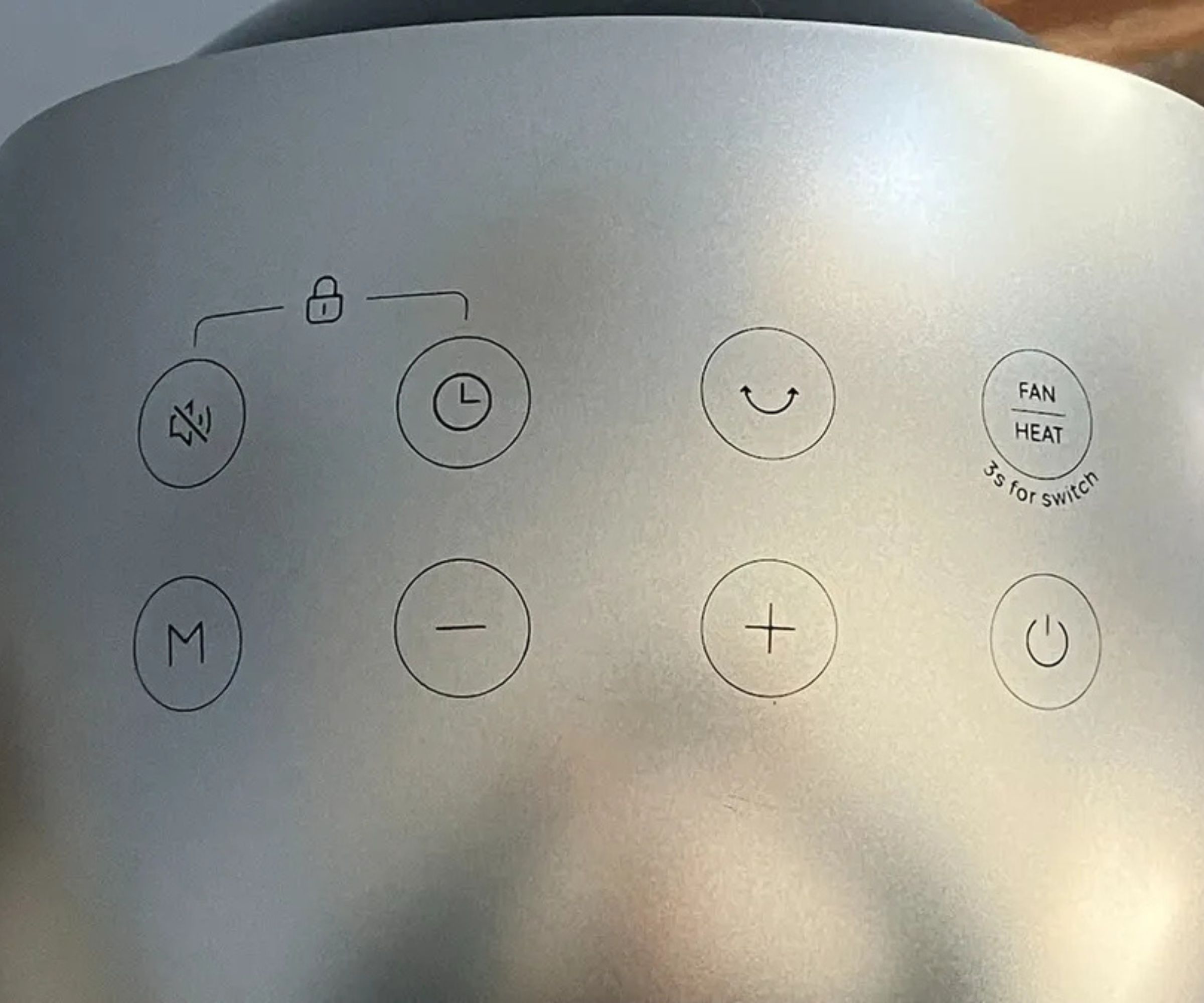 Photograph of the silver control panel of the Dreo 2-in-1 Tower Fan and Heater MC706 showing buttons for volume, timer, oscillation, fan/heat, mode, minus, plus and power.