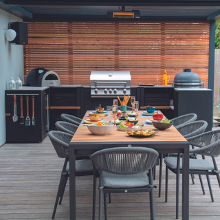 Covered outdoor kitchen area with table and rattan chairs and portable kitchen units