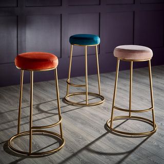 room with golden bar stool with blue pink and red seat and wooden flooring