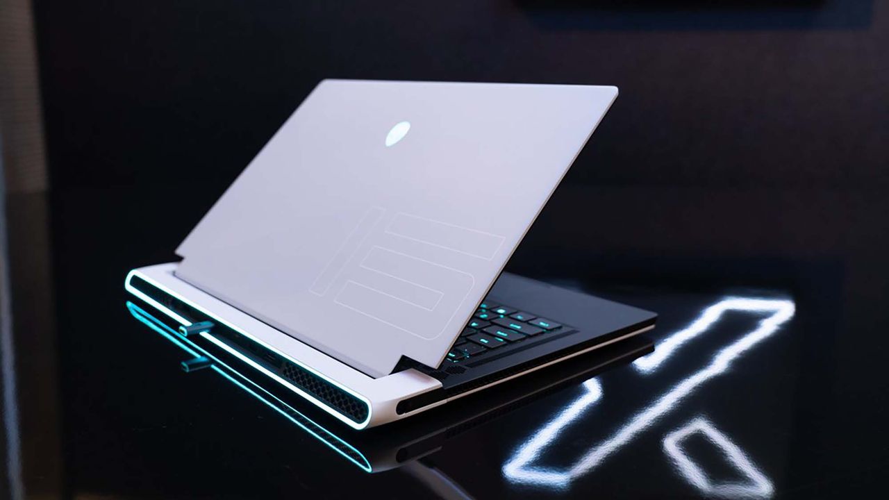 An Alienware gaming laptop on a table in a darkened room