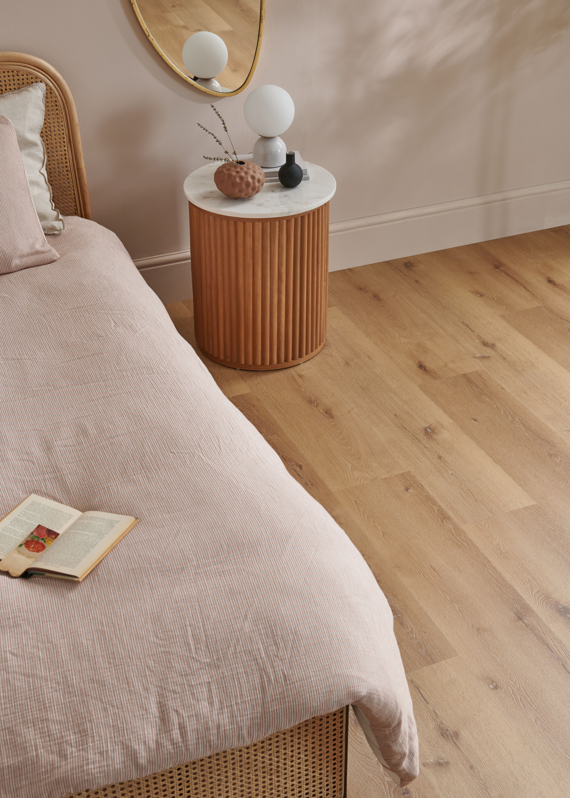 vinyl wood flooring in a bedroom with a fluted wooden bed and matching side table