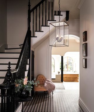 hallway with sweeping staircase, large glass pendant light and a black and white colour interior design scheme