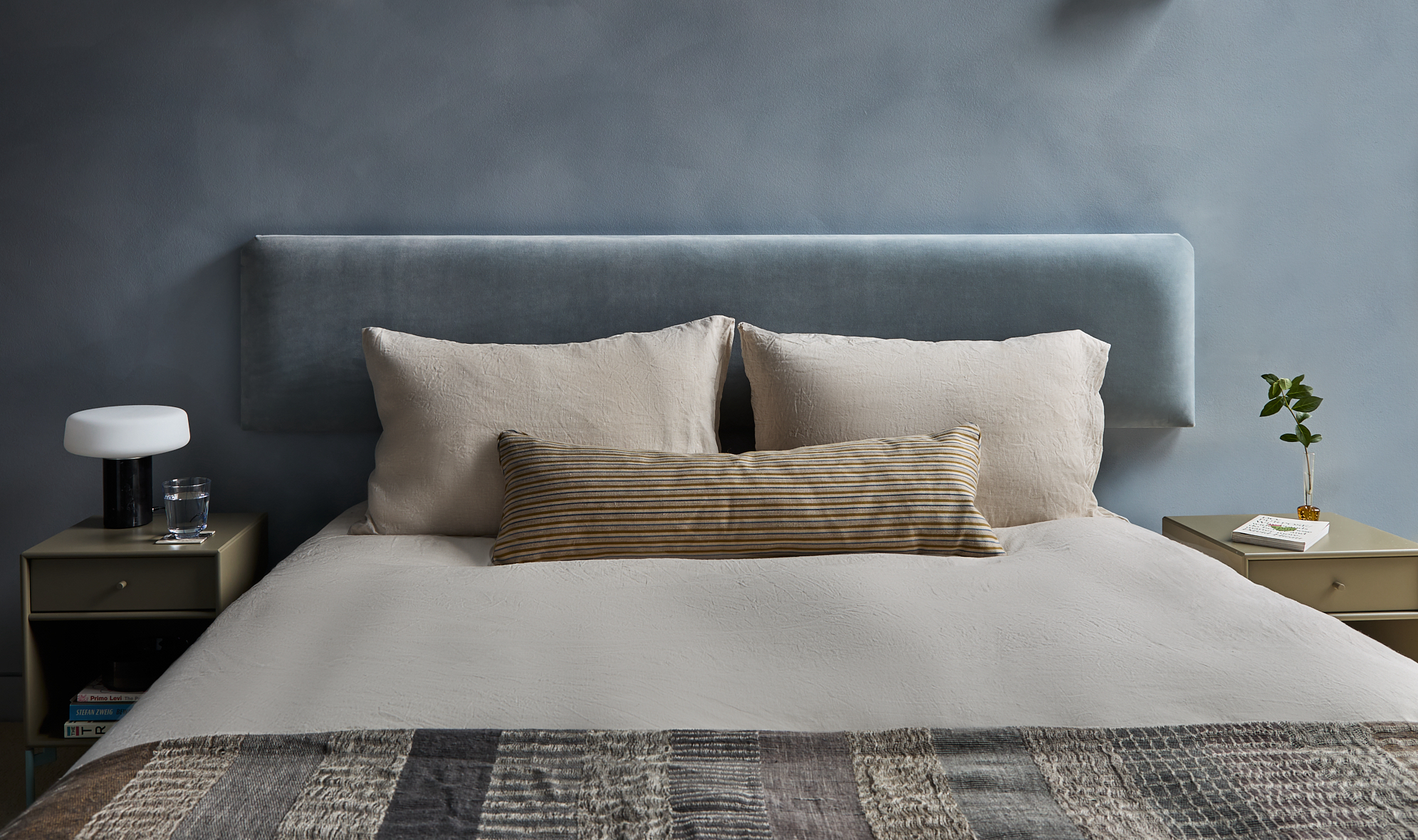 cool blue bedroom with limewash walls, velvet headboard and neutral linen
